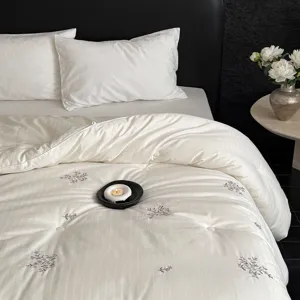 Edredón blanco acolchado con delicado bordado floral, ropa de cama cómoda para el dormitorio.