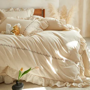 Détail en gros plan de la parure de lit en lin beige avec broderie florale délicate.
