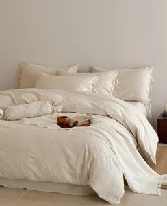 Close-up detail of cozy beige embossed jacquard bedding set with fringe throw blanket.