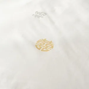 Close up view of luxury silk duvet fabric featuring traditional gold and silver blessing symbols.