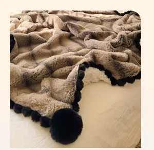 Luxury rabbit plush blanket detail, fluffy ripple texture with elegant black pom-pom trim.
