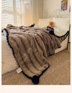 Luxury brown faux fur blanket with black pom pom trim, cozy plush fuzzy throw for bed.