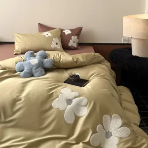 Close-up detail of luxury long-staple cotton bedding set with white towel embroidery flowers.