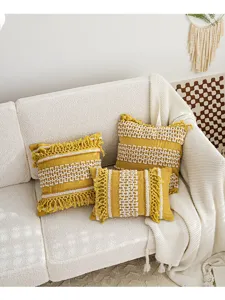 Housse de coussin touffetée bohème avec glands chics et motifs géométriques texturés.
