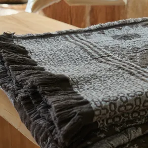 Close up detail of vintage woven cotton throw blanket with fringe on wooden table.