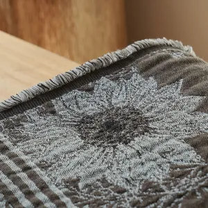 Close-up of vintage cotton jacquard throw blanket showing fine yarn-dyed floral texture and fringe.