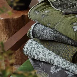 Close-up detail of vintage cotton jacquard throw blankets stacked on wooden chair decor.