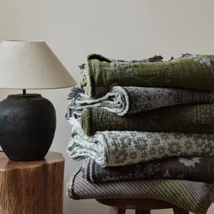 Detailed close-up view of vintage style cotton jacquard throw blanket with fringe detail in room.
