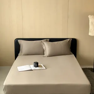 Detailopname van het luxe katoenen hoeslaken en kussenslopen in een warme beige slaapkamer.