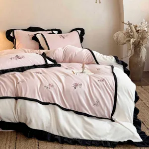 Gemütliche rosa Milchsamt-Bettwäsche Detail, weiche Rosenstickerei und schwarze Rüschen.