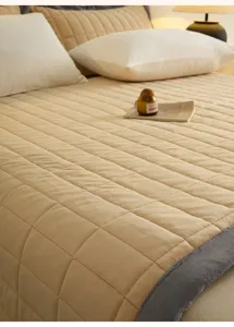 Detailed shot of thick quilted milk velvet bed cover in light beige, cozy bedroom texture.