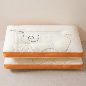 Ergonomisches Kissen Detail mit weichem Cremestoff, orangefarbenem Netzrand und Schafstickerei.