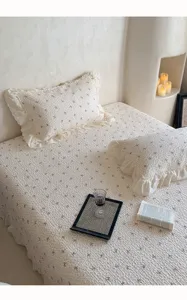 Vue détaillée du couvre-lit en double gaze de coton matelassé avec dentelle délicate et imprimé nœuds.