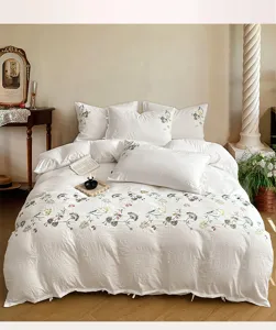 Vue détaillée de la parure de lit en coton lavé blanc avec une délicate broderie florale.