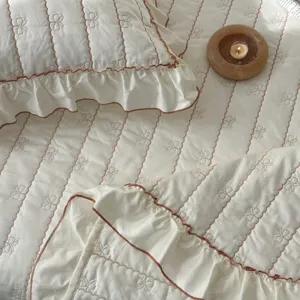 Colcha de algodón puro clase A con volantes elegantes y bordado de lazos acolchado.