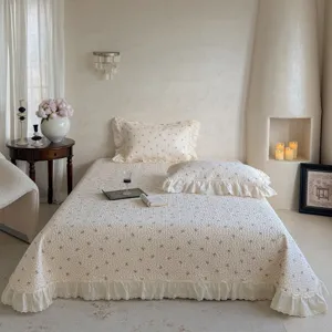 Couvre-lit matelassé à fleurs en coton avec volants en dentelle, esthétique de chambre chaleureuse.