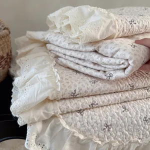 Couvre-lit matelassé en coton à imprimé floral délicat, nœuds gris et élégante bordure en dentelle.
