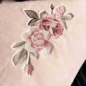 Nahaufnahme von weicher rosa Fleecébettwäsche mit einer exquisiten Rosenblumenstickerei.