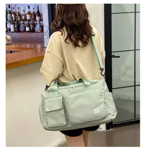 Detailansicht einer großen hellgrünen Sporttasche mit mehreren Taschen und Gurt.
