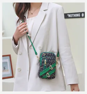 Stylish women crossbody phone bag with monogram print, green trim and cute heart charms.