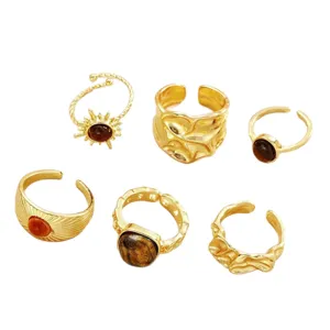 Set of six gold-toned adjustable open rings with irregular textures and amber-like stones.