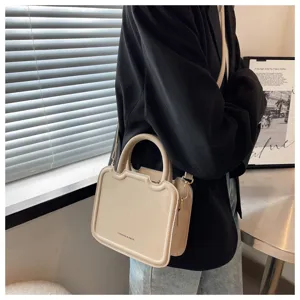 Close-up detail of trendy beige structured handbag featuring chic top handle and shoulder strap.