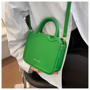 Green structured handbag detail showcasing sleek design, gold tone hardware and top handle.