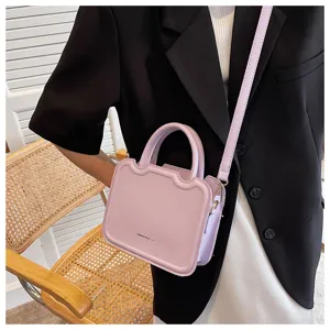 Detail view of a lavender purple handbag with a unique wavy top design and crossbody strap.