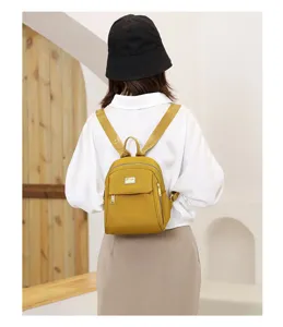Back view of a mini yellow nylon backpack for women with adjustable patterned straps.