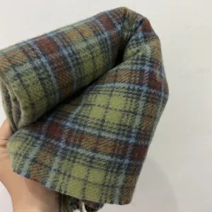 Close-up detail of a vintage green plaid winter scarf, soft texture and classic checkered pattern.