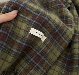 Green plaid scarf detail shot showing soft cozy texture, perfect winter accessory for women.