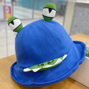 Close-up detail of cute blue monster bucket hat with 3D embroidered eyes and funny teeth.