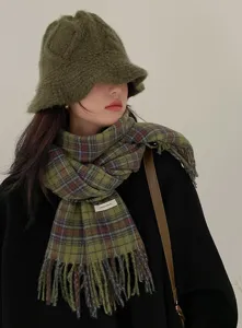 Close-up detail of green plaid scarf and matching knitted bucket hat for winter fashion.