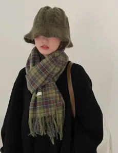 Close-up of green plaid winter scarf featuring cozy fringe edges and soft texture.