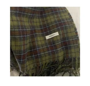 Close-up detail of the vintage green and brown plaid scarf featuring soft textured fabric and chic fringe hem.