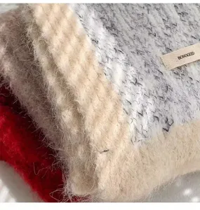 Close-up detail of cozy fuzzy winter plaid wool blend scarf texture with brand label.