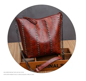 Brown soft leather shoulder bag detail featuring metal studs and chain strap design.
