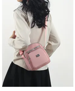 Detail view of pink nylon crossbody bag with multi-layer zipper compartments and strap.
