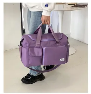 Detalle de bolsa de viaje morada con bolsillos frontales, tela resistente y correa.
