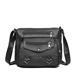 Detail view of black soft leather crossbody bag featuring multiple zippered pockets.