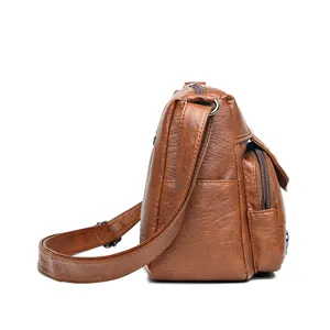 Side view detail of women vintage brown soft leather crossbody shoulder bag with zippers.