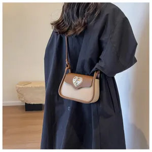Vista dettagliata della borsa bicolore con elegante chiusura a cuore in metallo e tracolla.