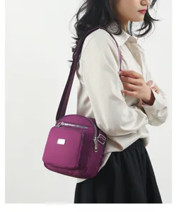 Detail view of a compact purple nylon crossbody shoulder bag for daily women use now.