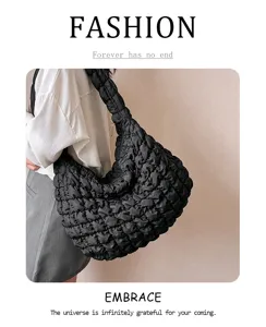 Detailed shot of trendy black quilted shoulder bag, showing puffy texture and large capacity.
