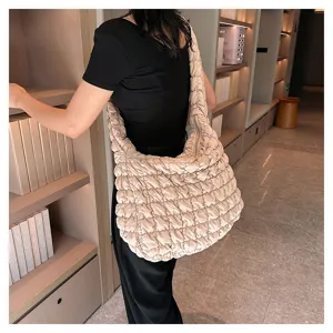 Detail shot of a trendy beige quilted shoulder bag, casual puffer hobo tote for women.
