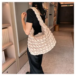 Detail shot of a stylish beige quilted puffer shoulder bag, soft large capacity tote design.