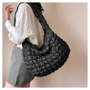 Close-up detail shot of a black quilted puffer shoulder bag worn by a model, casual and chic.