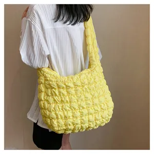 Detail shot of the bright yellow quilted shoulder tote bag showing puffy texture and capacity.
