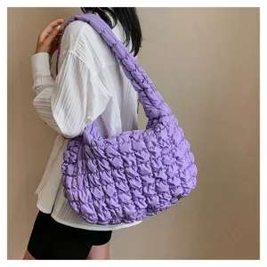 Detailed view of the purple quilted puffer shoulder bag, featuring soft textured fabric.