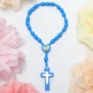Blue wooden rosary bracelet detail with oval pine beads, heart centerpiece and cross pendant.